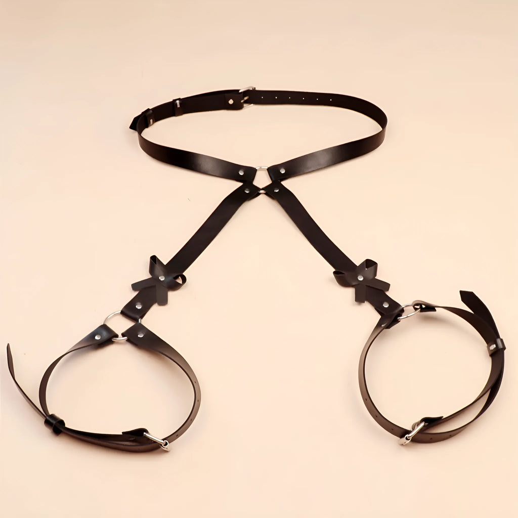 Black leather-look belt with metal buckle and bow detail, handcuffs from same set, on a dark surface