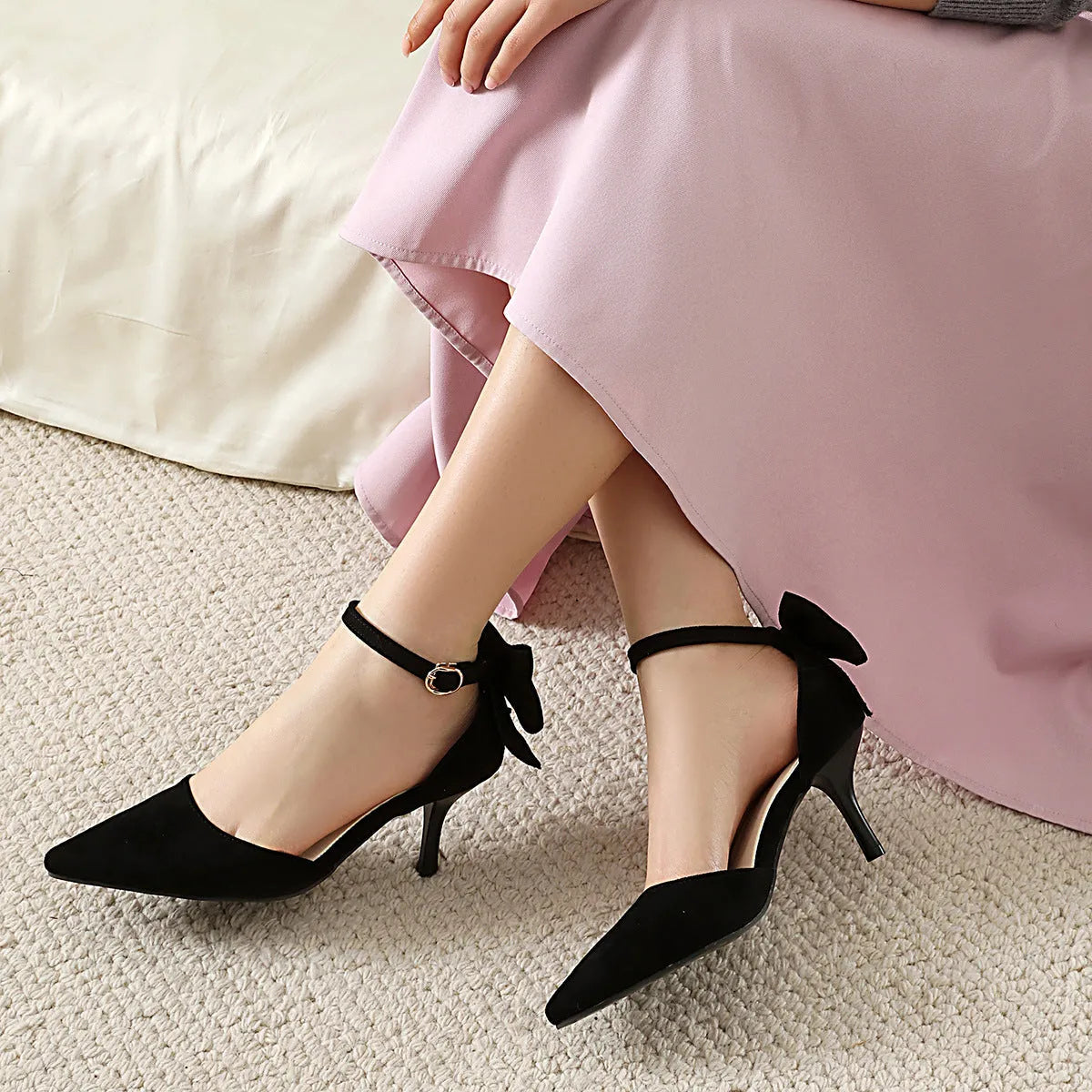 Black suede pointed-toe high heels with a bowknot and stiletto heel on a white background.