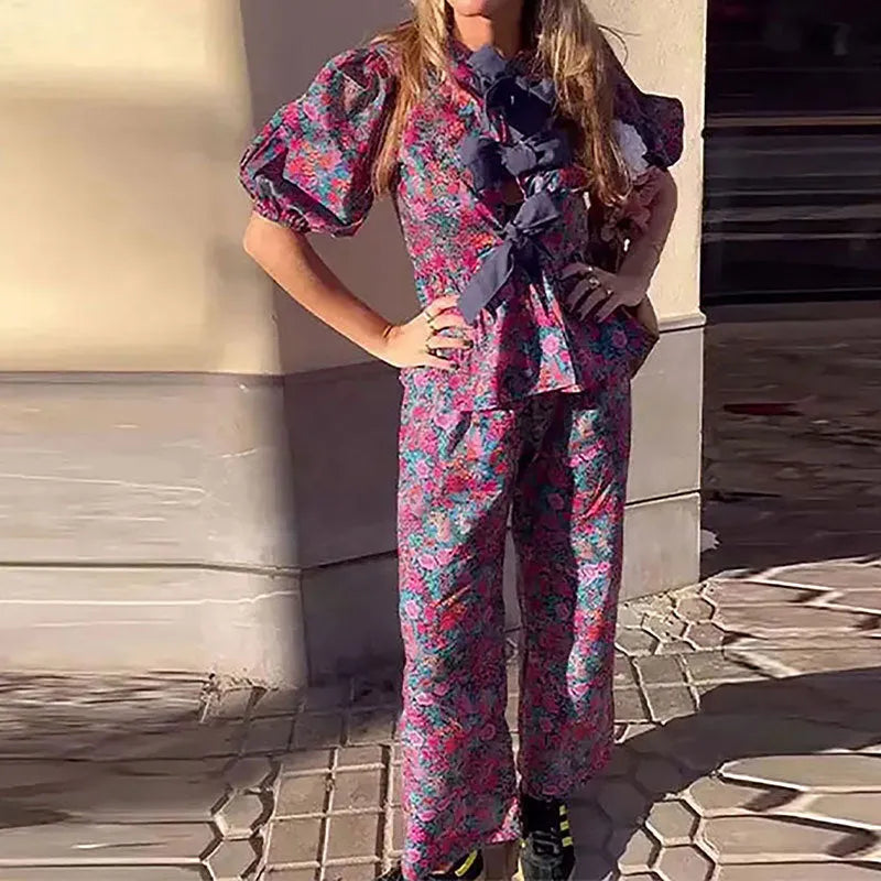 Women's floral print trousers suit with a tie-neck puff sleeve top and matching trousers