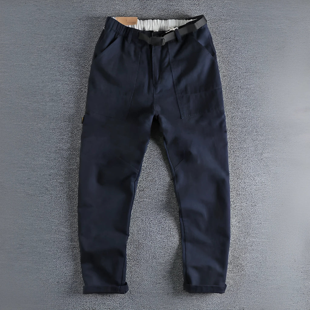 A pair of men's khaki cotton work trousers with a mid waist and zip fly on a plain background.