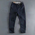 A pair of men's khaki cotton work trousers with a mid waist and zip fly on a plain background.