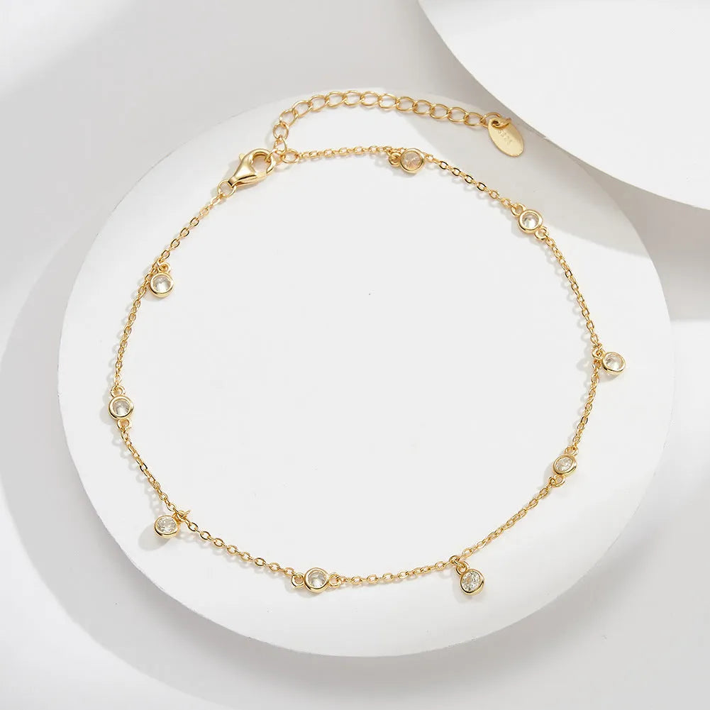 Women's silver geometric anklet with a small zirconium pendant, shown in gold and white gold colour options.