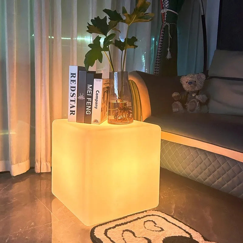 A white, square LED cube light stool with a modern design, shown outdoors on a patio.