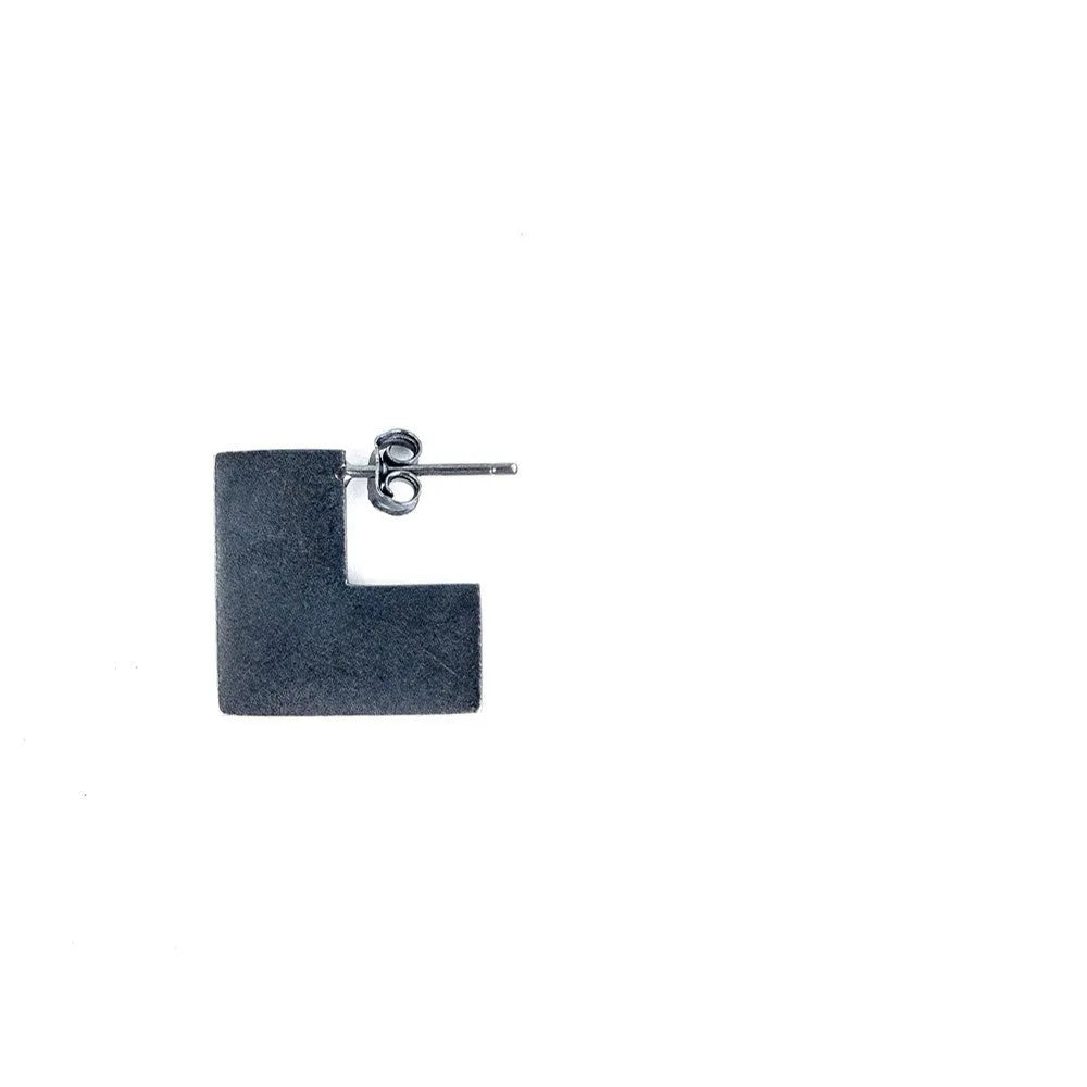 Close-up of oxidised black geometric square sterling silver ring-style earrings on a grey background.