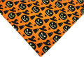 Reversible Halloween dog bandana with pumpkin and spider web patterns in black and orange