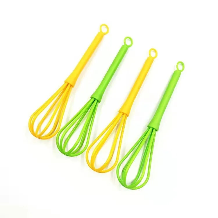 Plastic mini manual eggbeater in green for stirring batter in a kitchen