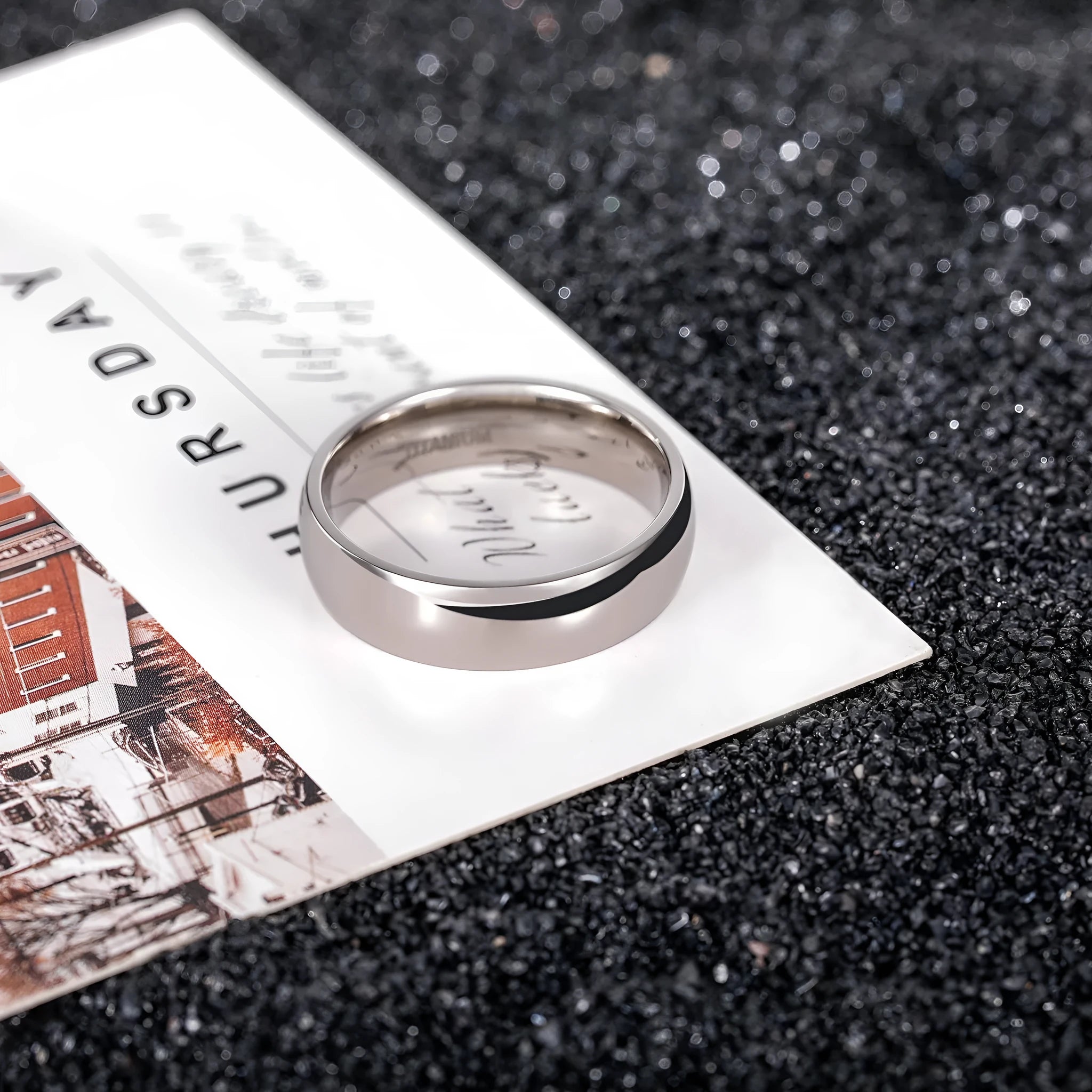 Simple silver-coloured titanium steel band ring with a matte finish on a grey background.