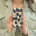 Black silicone iPhone case with a raised embossed tulip flower design on the back.