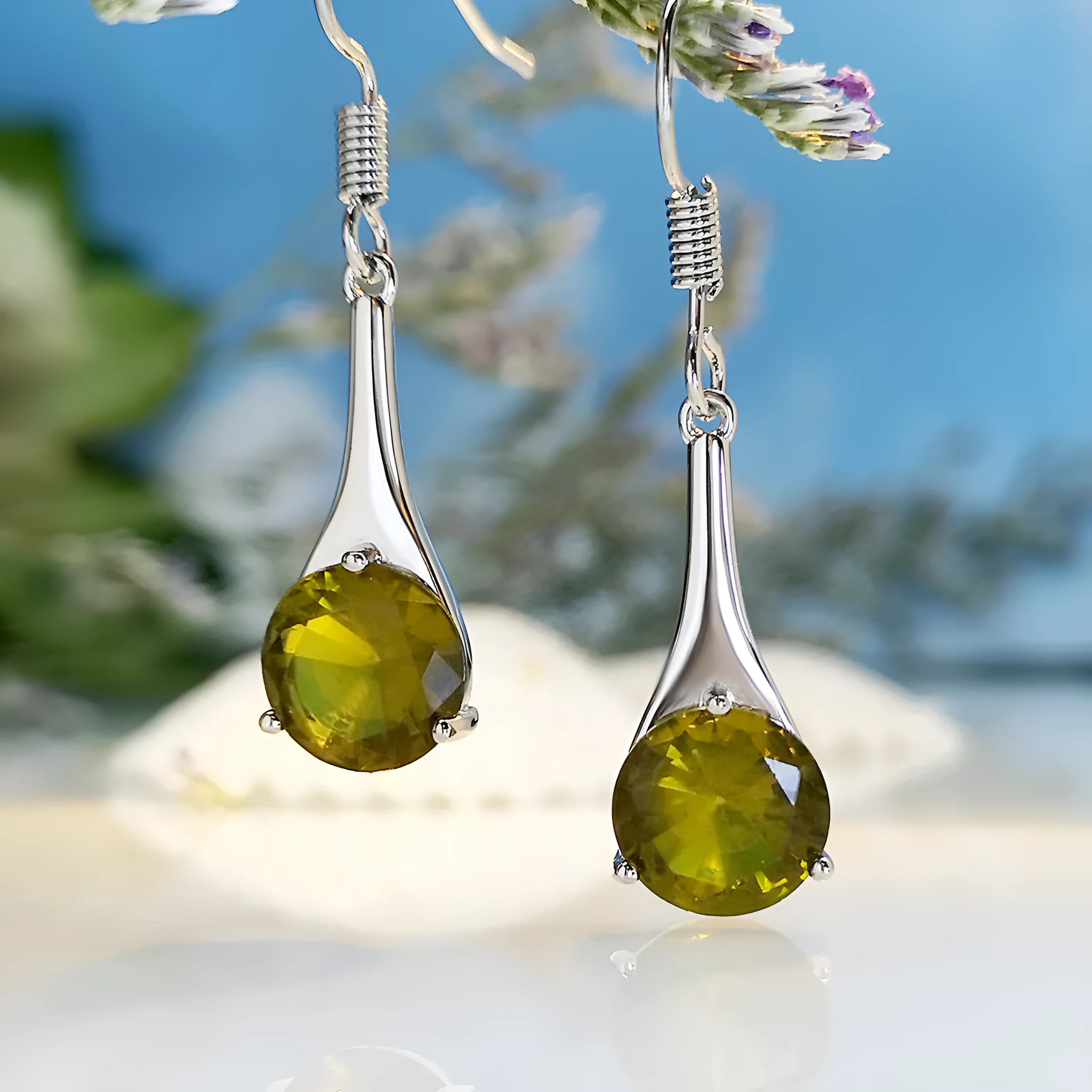 Olive green topaz coloured water drop shape earrings with minimalist retro styling on white background