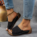 Women's black wedge beach slippers with floral cutouts on the PVC upper and a rubber sole.