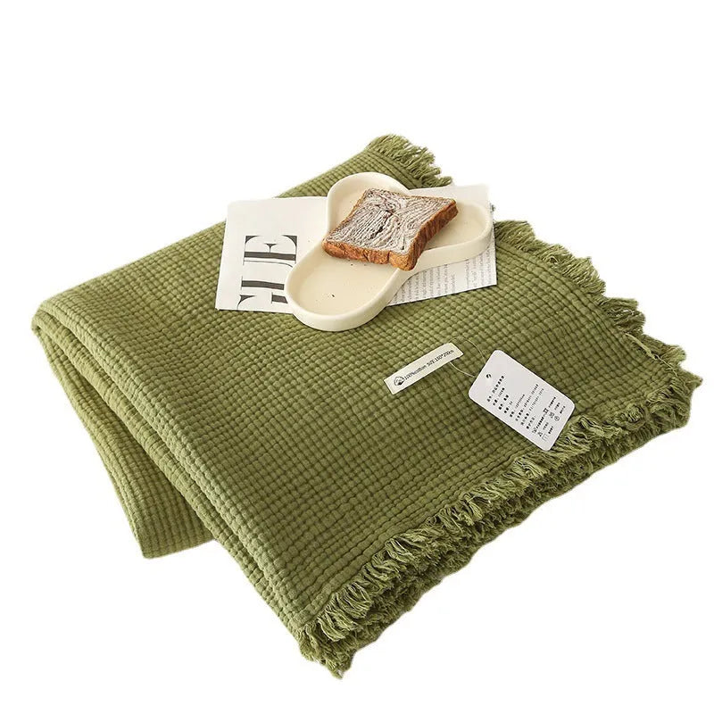 Four-layer gauze cotton blanket with tassel trim in navy blue colour, laid flat.