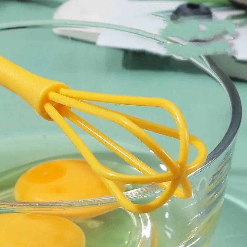 Plastic mini manual eggbeater in green for stirring batter in a kitchen