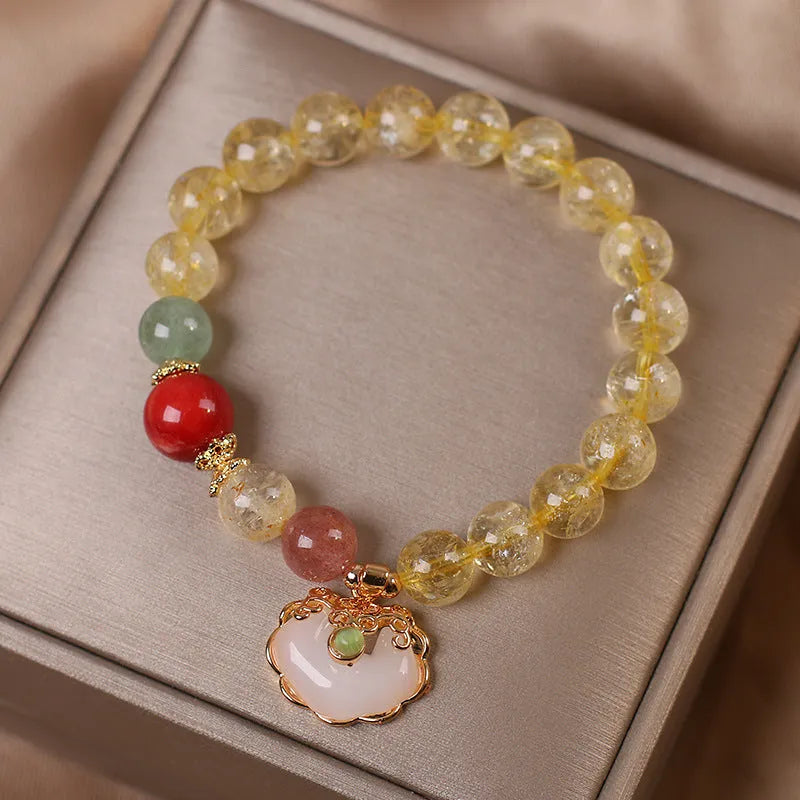 Close-up of a women's alloy bracelet with a yellow citrine jade ruyi pendant.