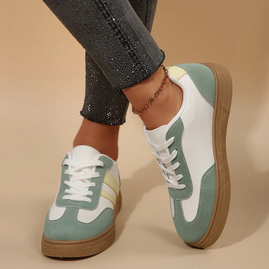 Green women's retro low-top trainers with cross-strap detail and round toe on a white background.