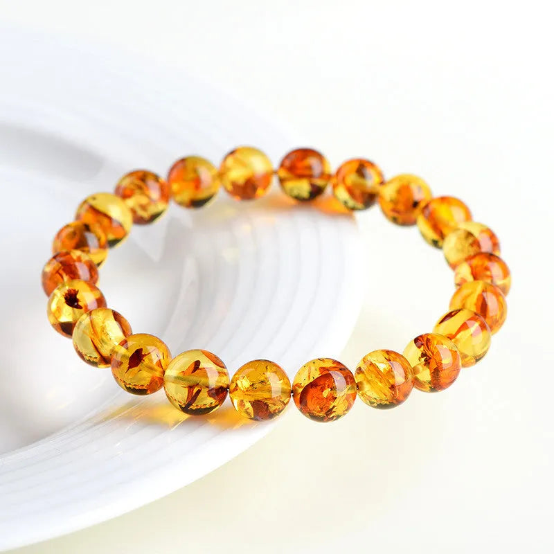 Natural yellow amber bracelet with piebald spots, showing geometric beads on a wrist.