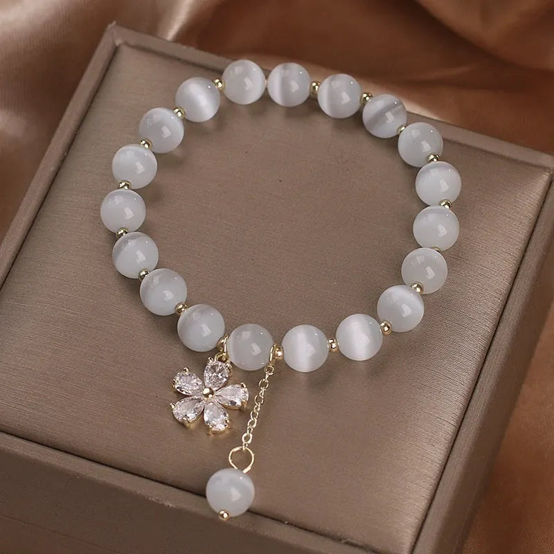 White Cat's Eye stone bracelet with a small flower tassel pendant and a safety buckle.