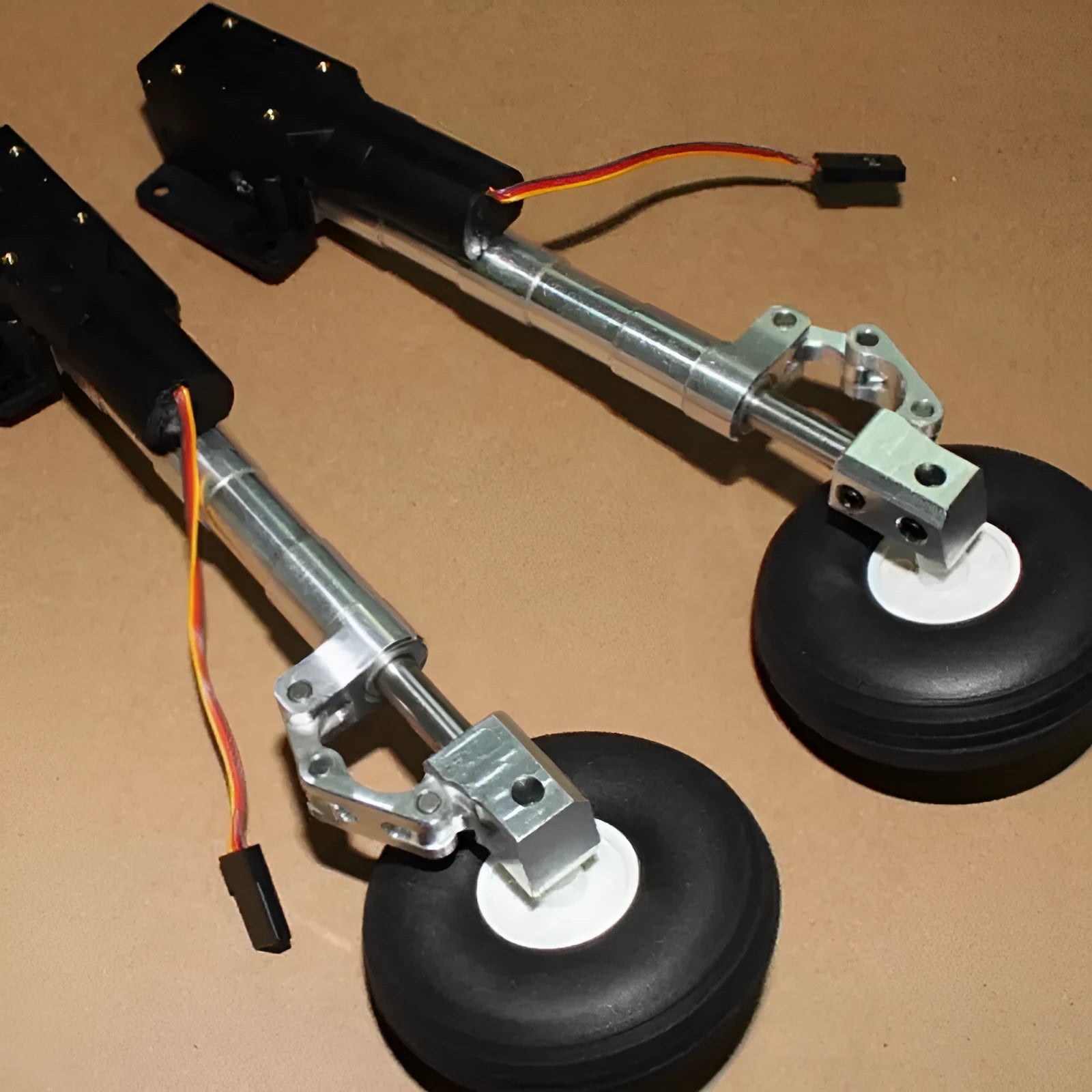 Pair of silver alloy retractable landing gear for RC models with wheels, shown at an inclined kneeling angle.