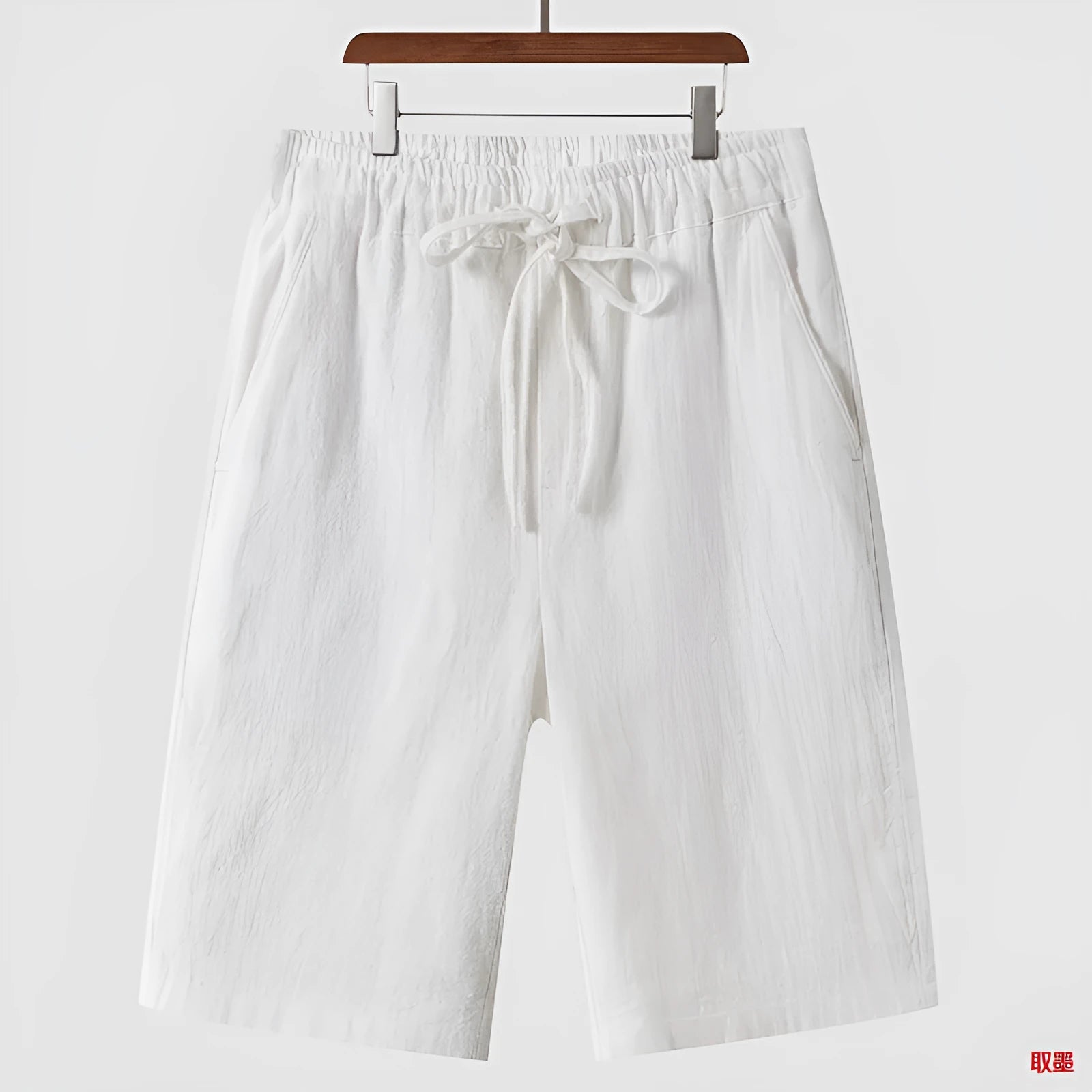 Men's beige linen loose cropped casual shorts on a neutral background.