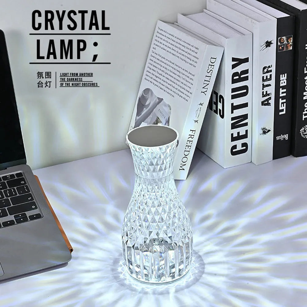 Transparent vase-shaped crystal LED table lamp on a table, showing soft coloured light.