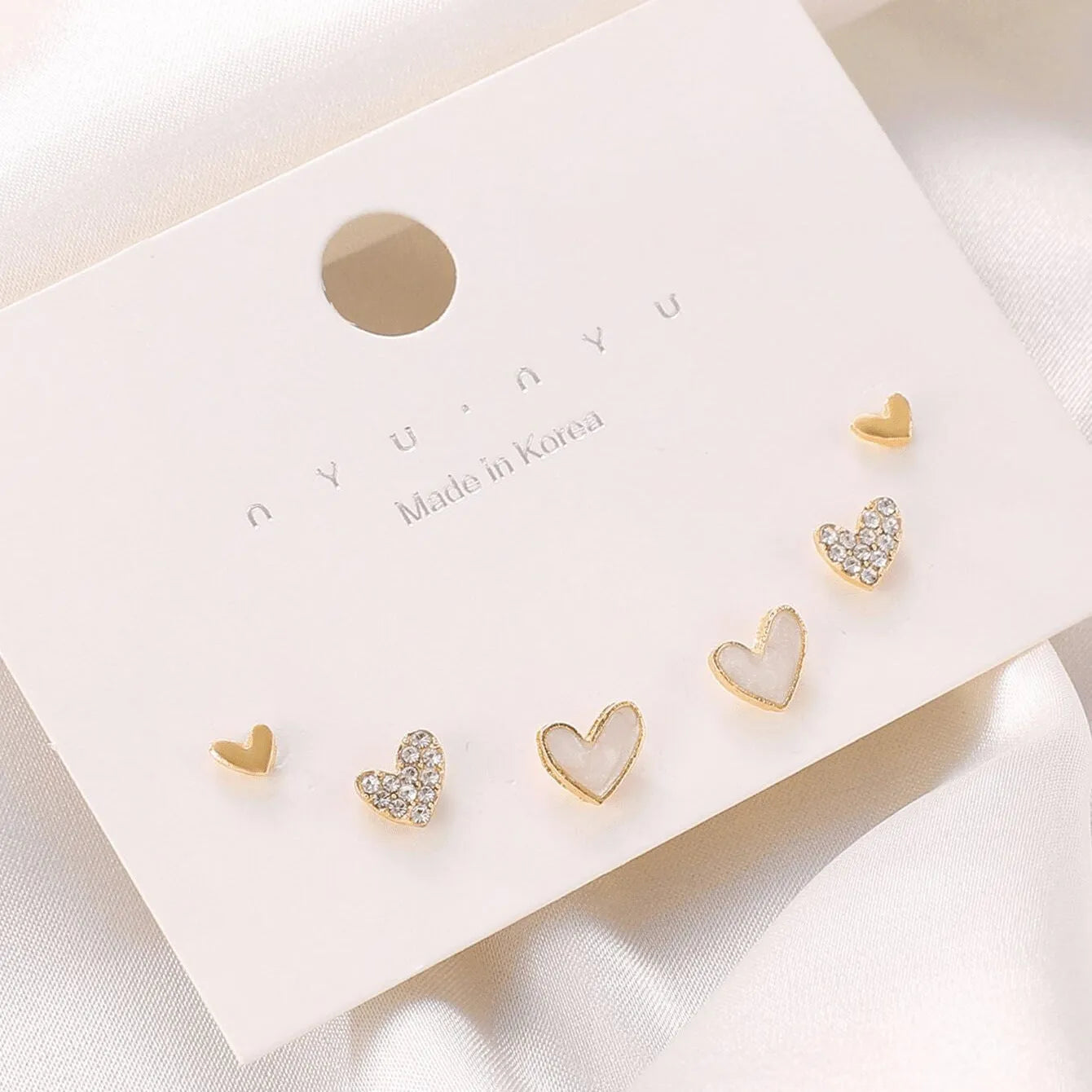Three pairs of heart-shaped women's earrings in gold, black, and pink colour options