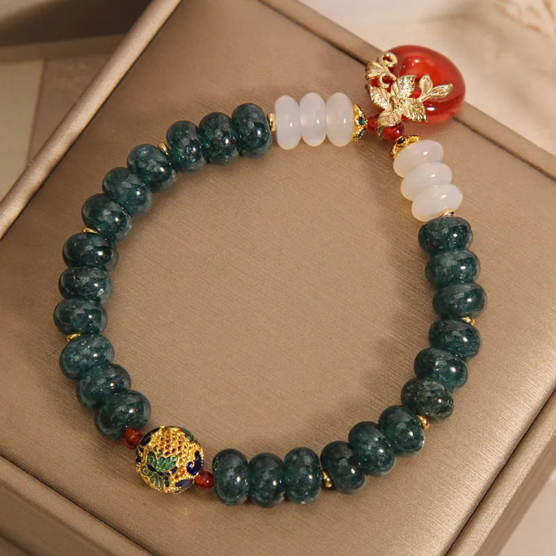 Close-up of a women's crystal bracelet with blue jade beads, red agate, and a silver peace buckle closure.