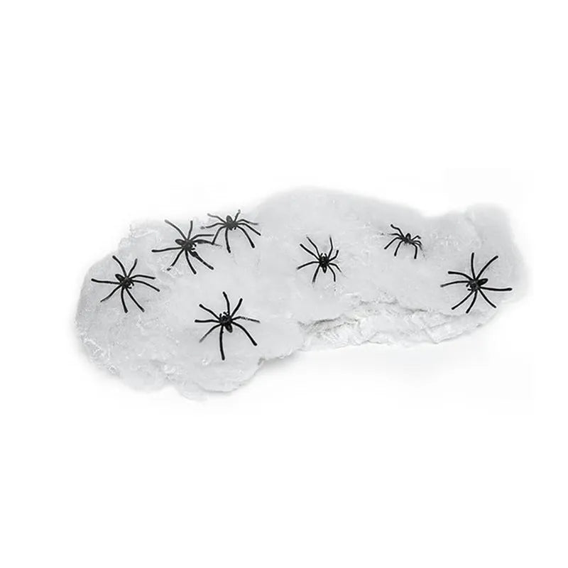 White cotton spider web Halloween decoration with plastic spiders draped over a surface.