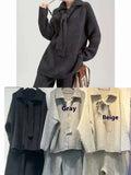 Women's beige knitted top and matching trousers from a two-piece acrylic sweater suit set laid flat.