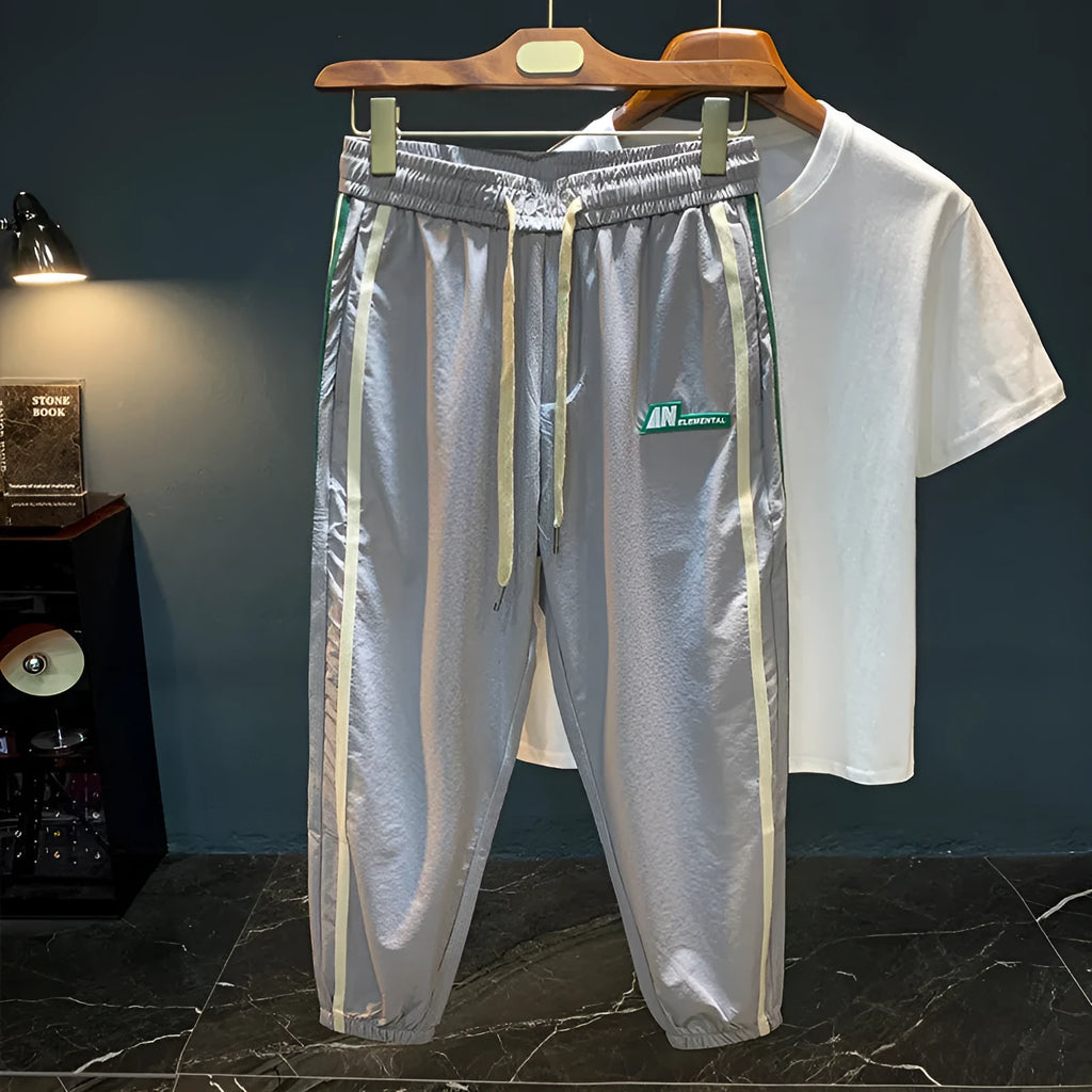 Black men's cotton harem trousers with a dropped crotch and tapered leg on a grey background.