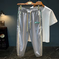 Black men's cotton harem trousers with a dropped crotch and tapered leg on a grey background.