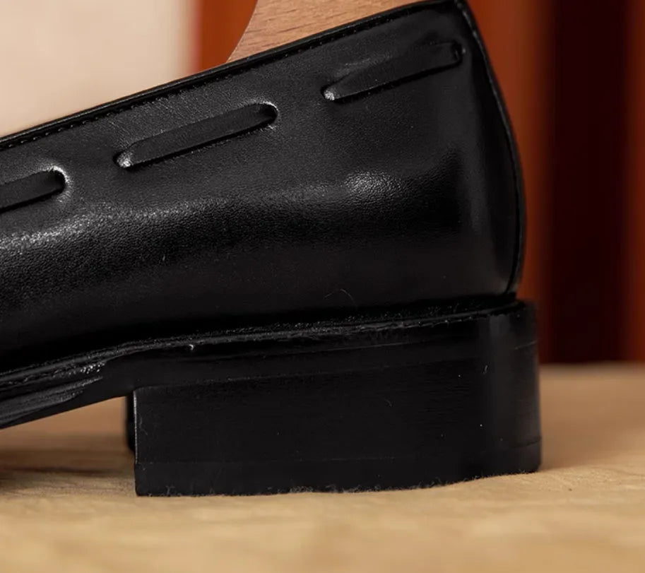Men's black leather slip-on loafers with a fringed detail on the vamp and a rubber sole.