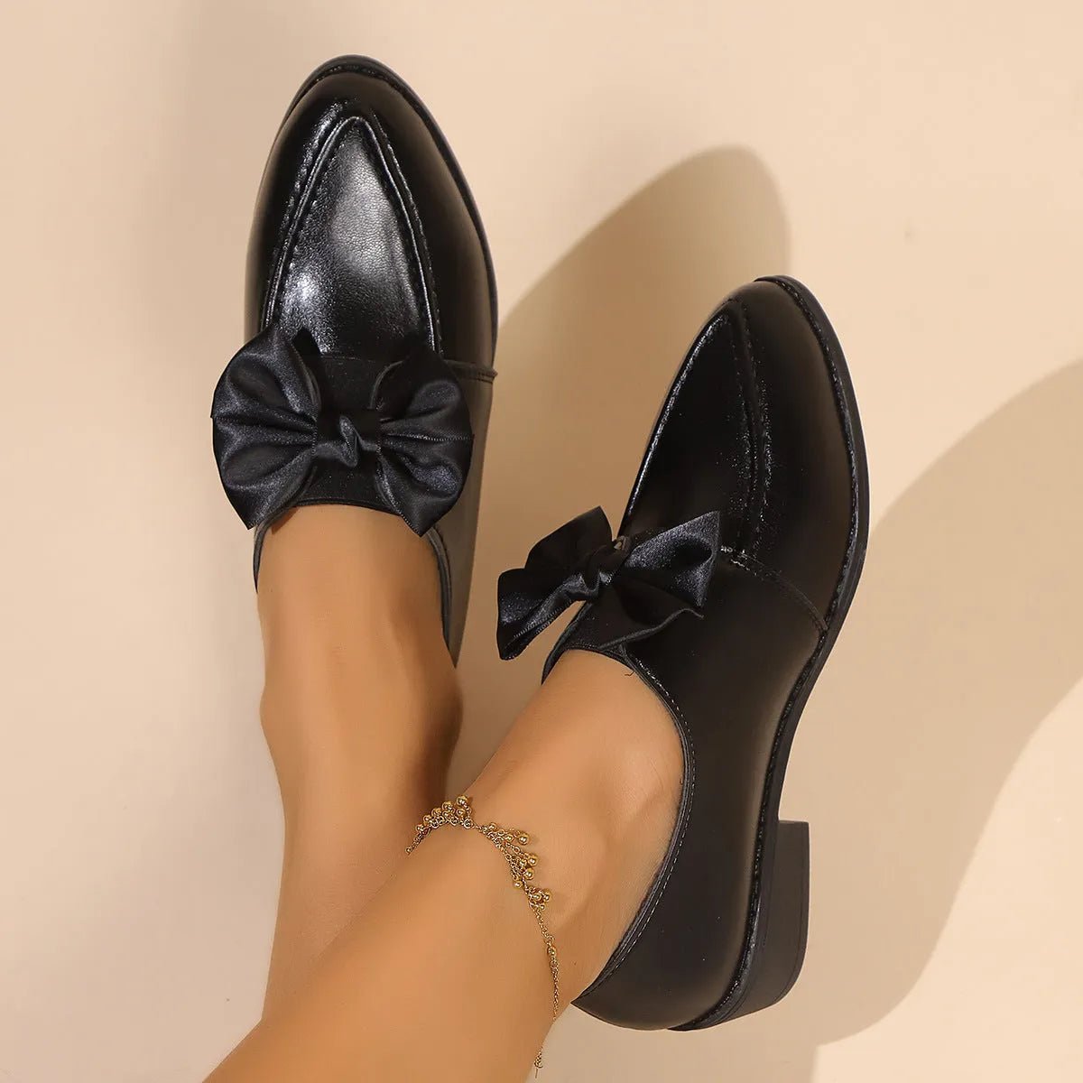 Women's classic black slip-on flat shoes with a large decorative bow on the toe.