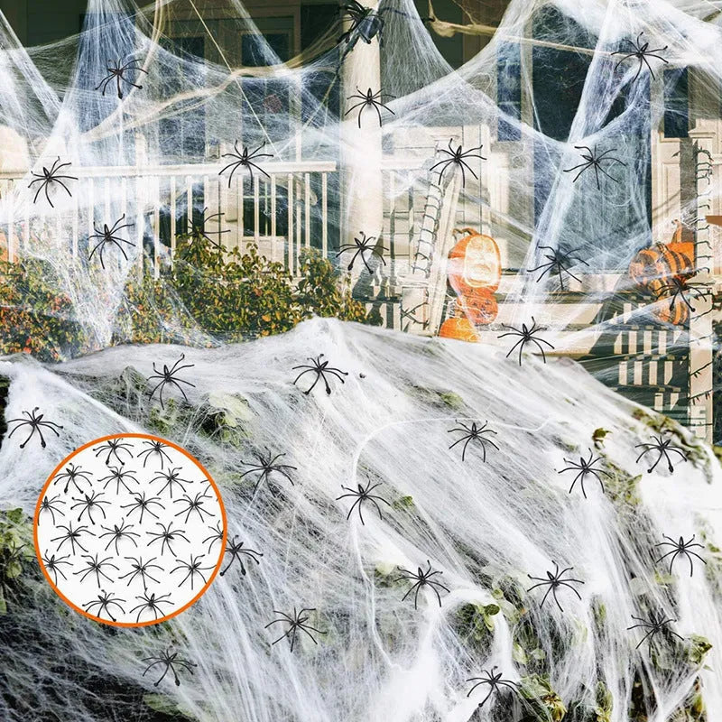 White cotton spider web Halloween decoration with plastic spiders draped over a surface.