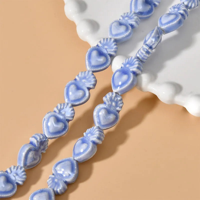 Small heart-shaped ceramic beads in multiple colours showing straight hole, approximately 10mm by 15mm size