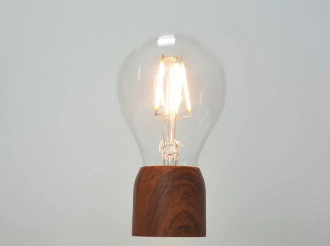 Magnetic levitation floating light bulb hovering above a wood-effect base.