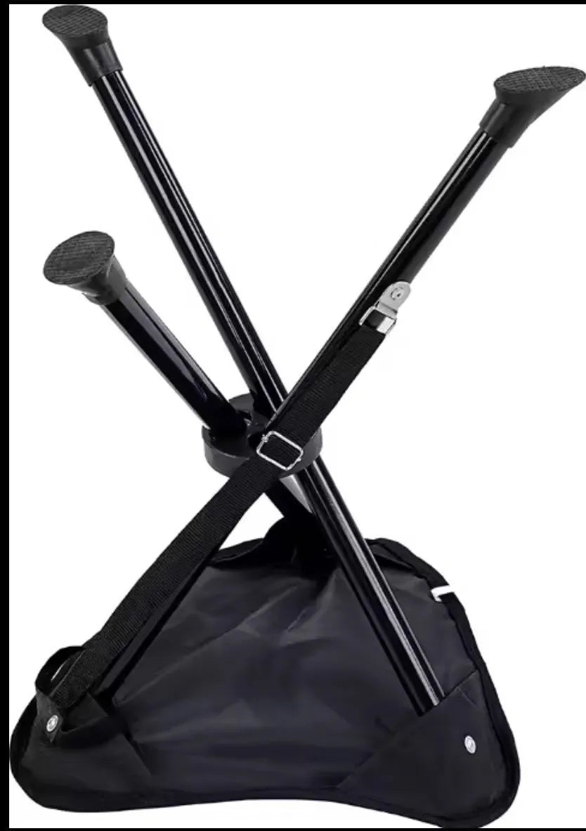 Green folding camping stool with aluminium tripod legs set up outdoors on grass