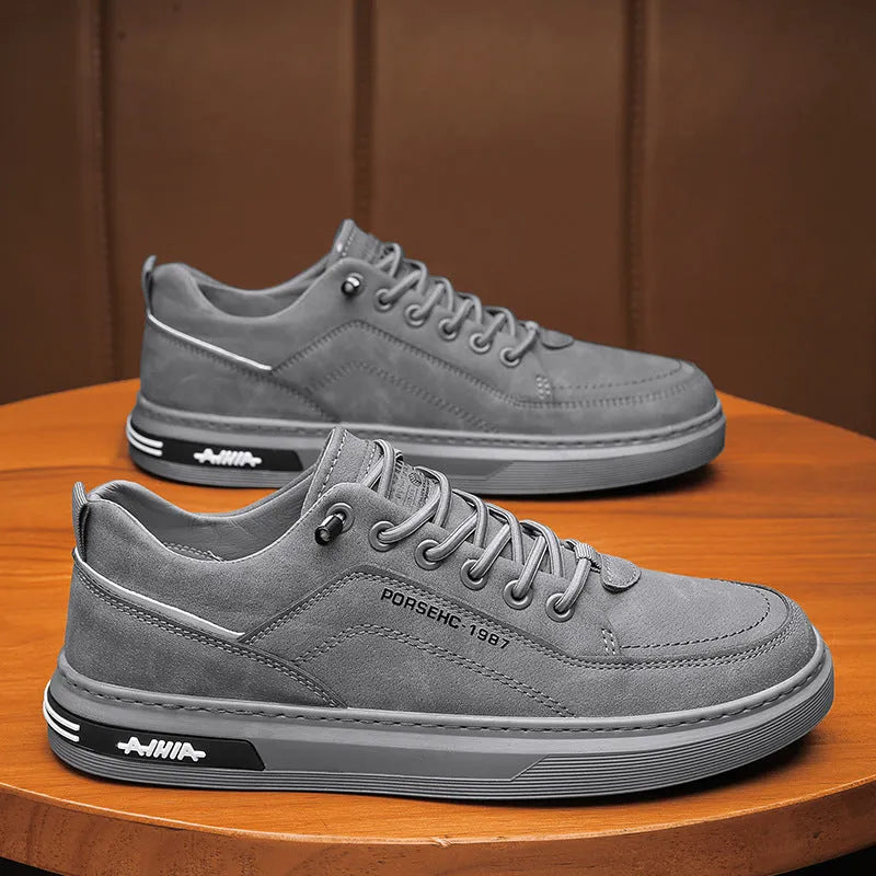 Men's low-top casual shoes in khaki with a round toe and rubber sole, shown on a work site background.