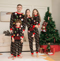 Family wearing matching red plaid Christmas pyjamas with dog in coordinating pyjamas