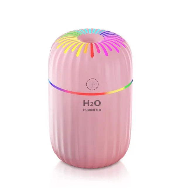 White USB mini humidifier with water tank on a desk next to a laptop