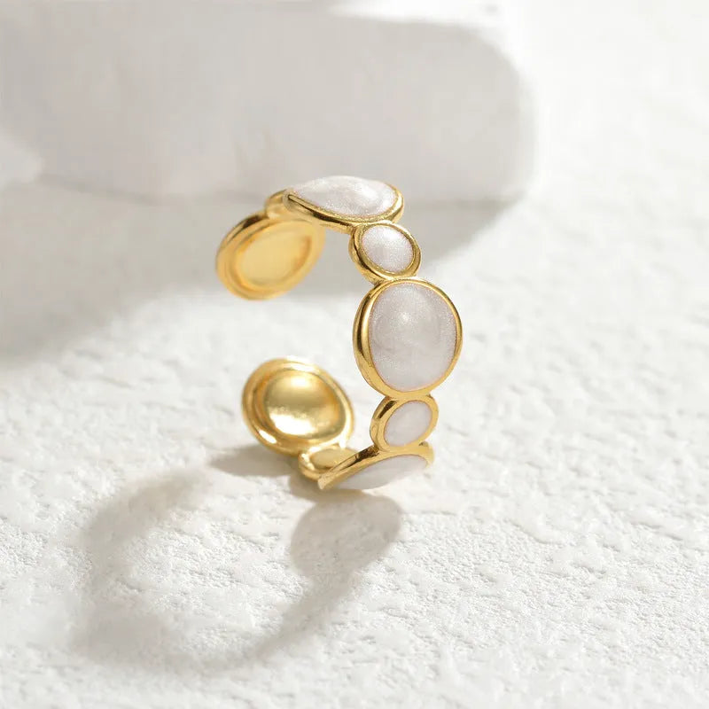 A geometric stainless steel ring with an adjustable opening on a plain background.
