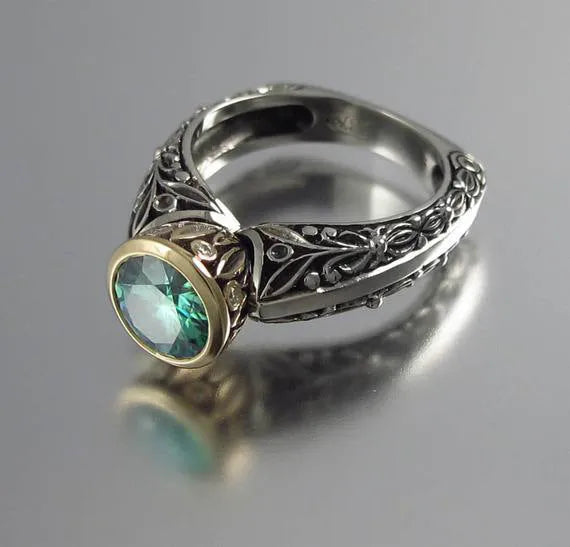 Flower-shaped gold-plated vintage ring with green gemstone and colour separation design on finger