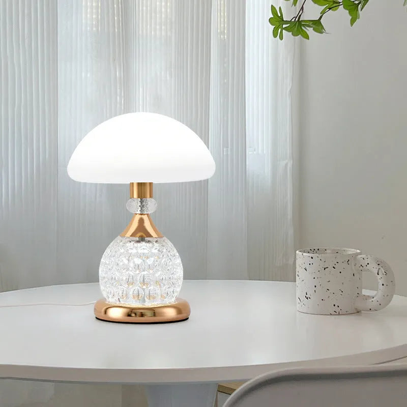 Light luxury mushroom table lamp in transparent colour option on a bedroom desk with USB cable connected.