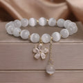 White Cat's Eye stone bracelet with a small flower tassel pendant and a safety buckle.