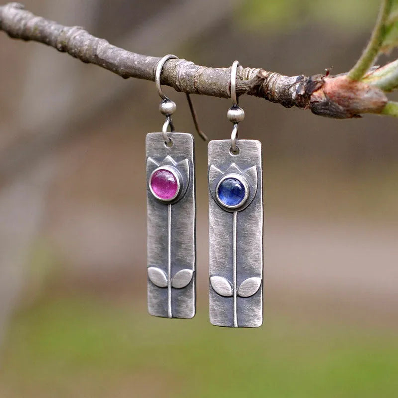 A pair of women's geometric earrings with an antique red finish and elliptical design details.