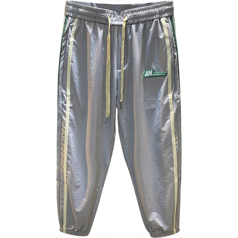 Black men's cotton harem trousers with a dropped crotch and tapered leg on a grey background.