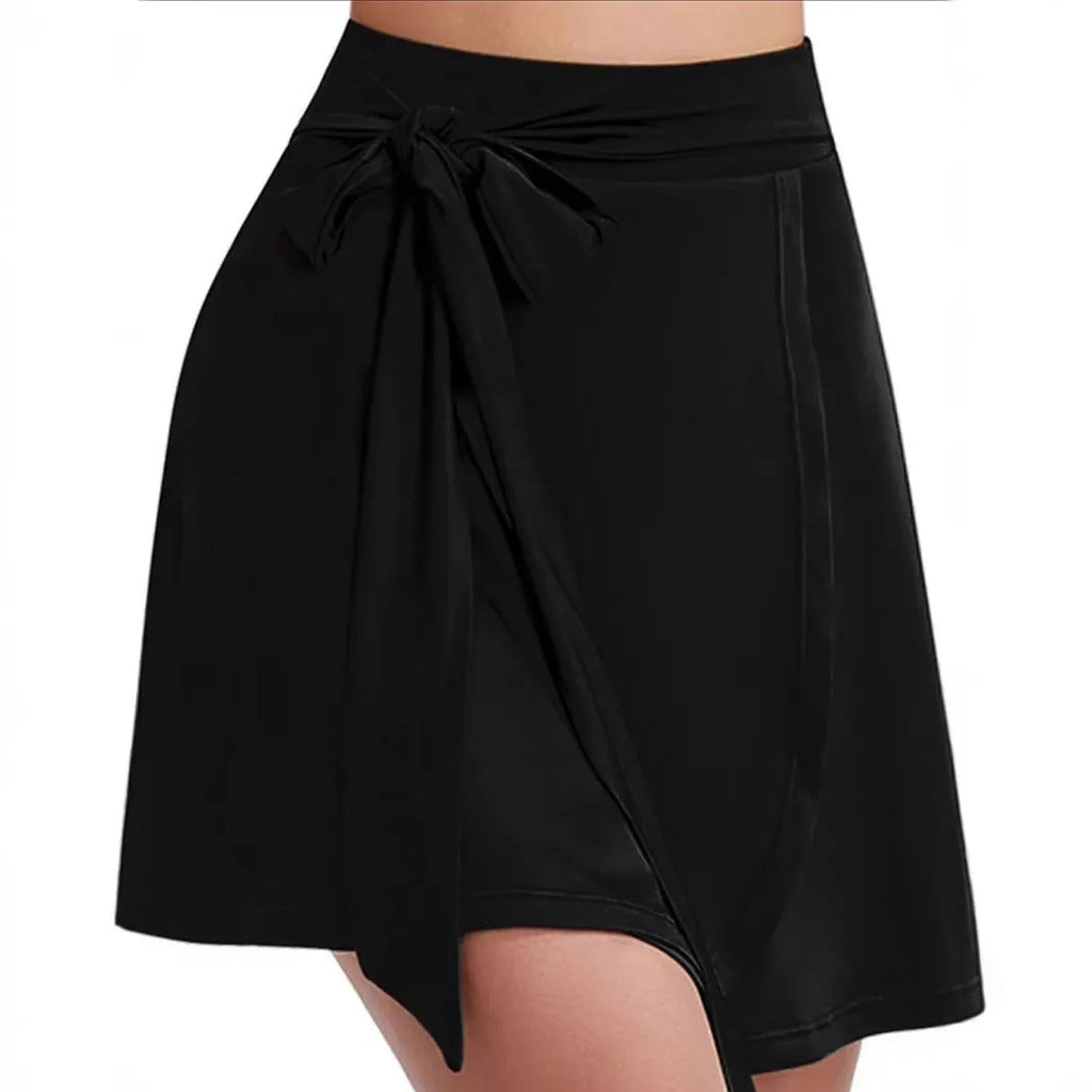 Black thigh-length sports skirt with high waist and shoulder strap detail on a model.