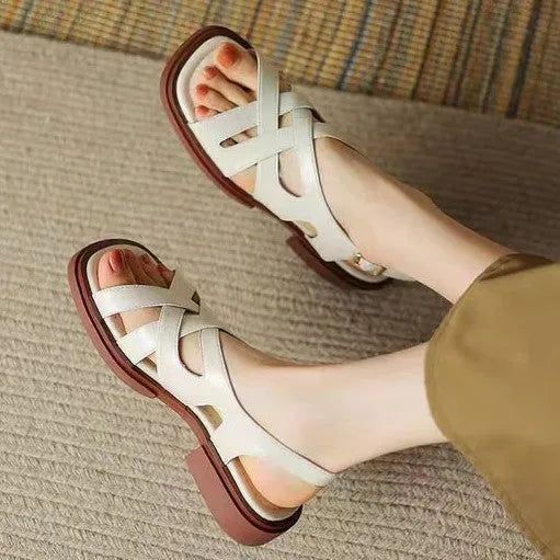 Women's glossy black patent leather sandals with square toe and cross ankle strap.