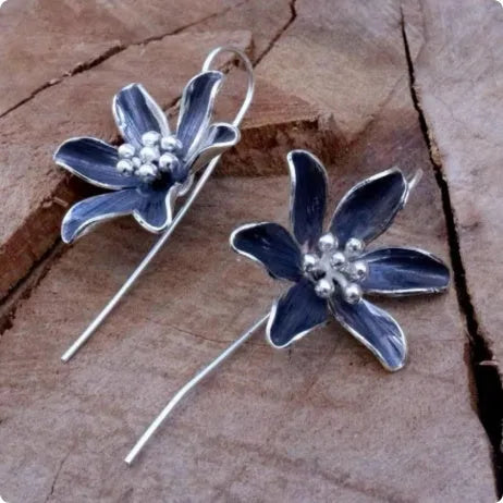 A pair of purple flower-shaped alloy drop earrings with a retro design on a white background.