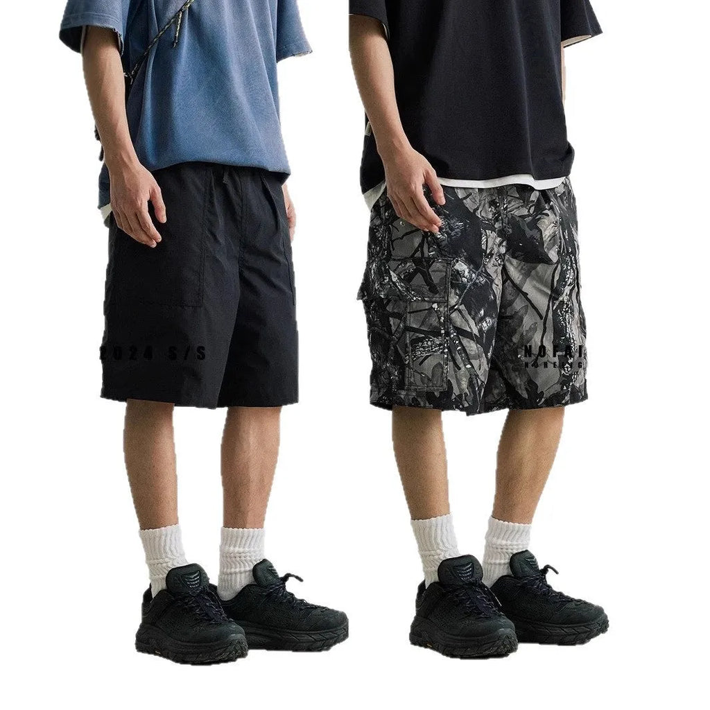 Loose fit straight-leg denim shorts in black or army green on a hanger, showing mid-waist and zip fly detail.