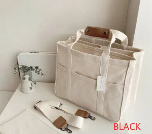 Beige canvas crossbody mommy bag holding baby bottles and wipes on table