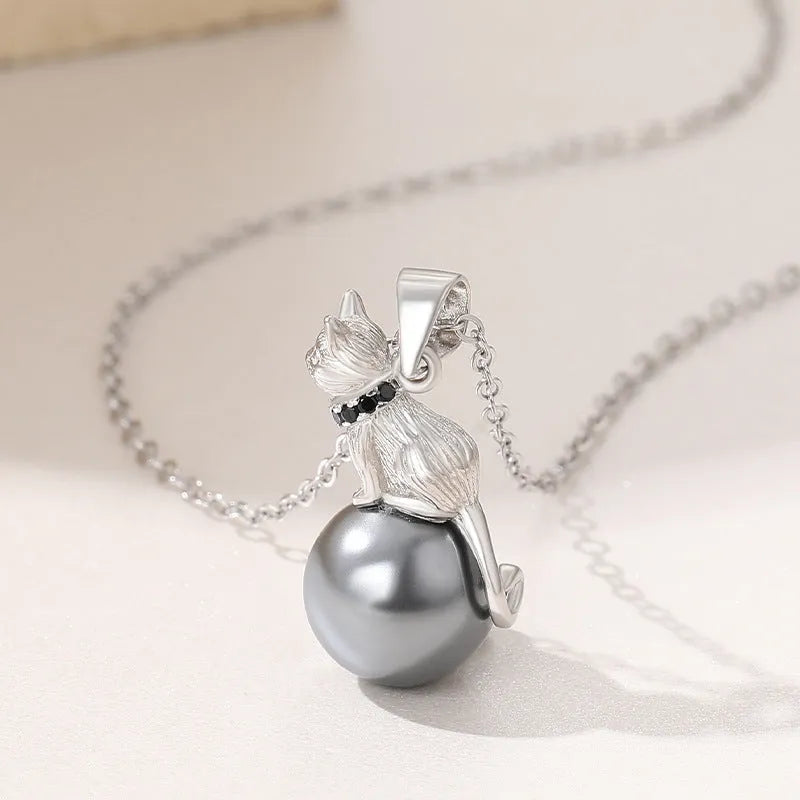 Close-up of a sterling silver cat pendant necklace on a clavicle, showing the electroplated finish.